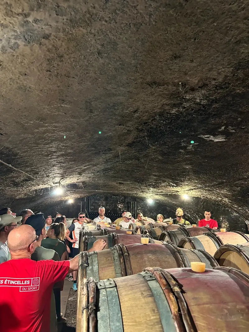 Visite de cave : le groupe écoute le vigneron entre les fûts de chêne